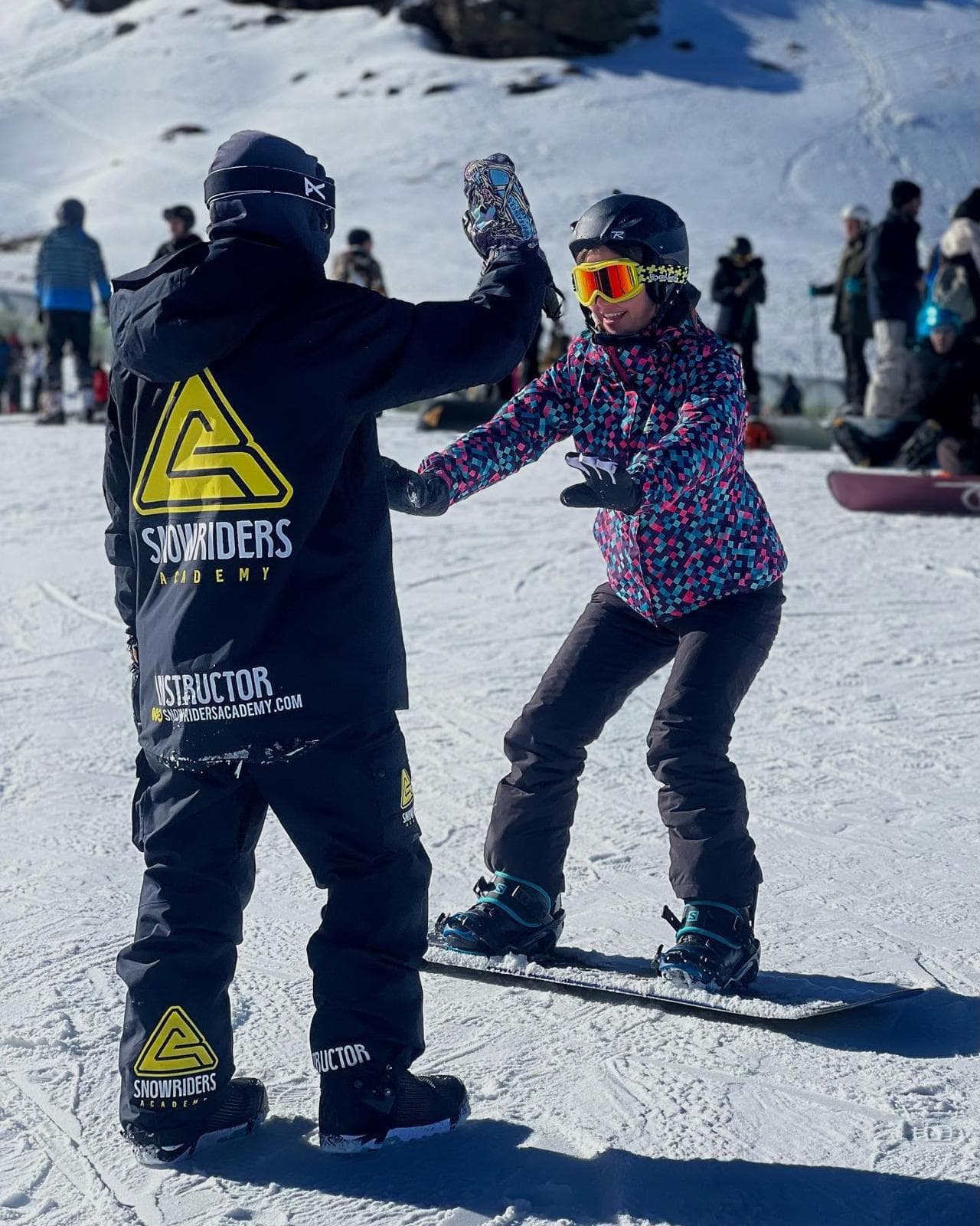 Instructor de Snowbound Academy chocando la mano con una alumna en la nieve